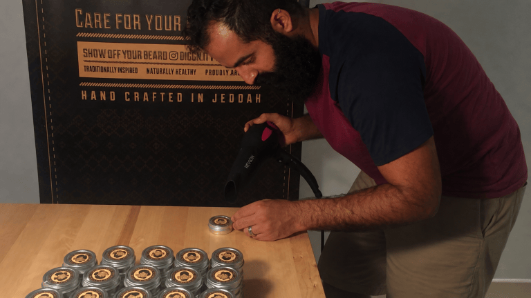 AI-edited image of Waseem using a heat gun to seal Diggn’It tins at an early production table in Jeddah.